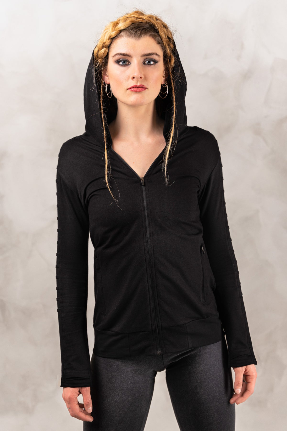 a woman wearing a black hoodie and black leggings