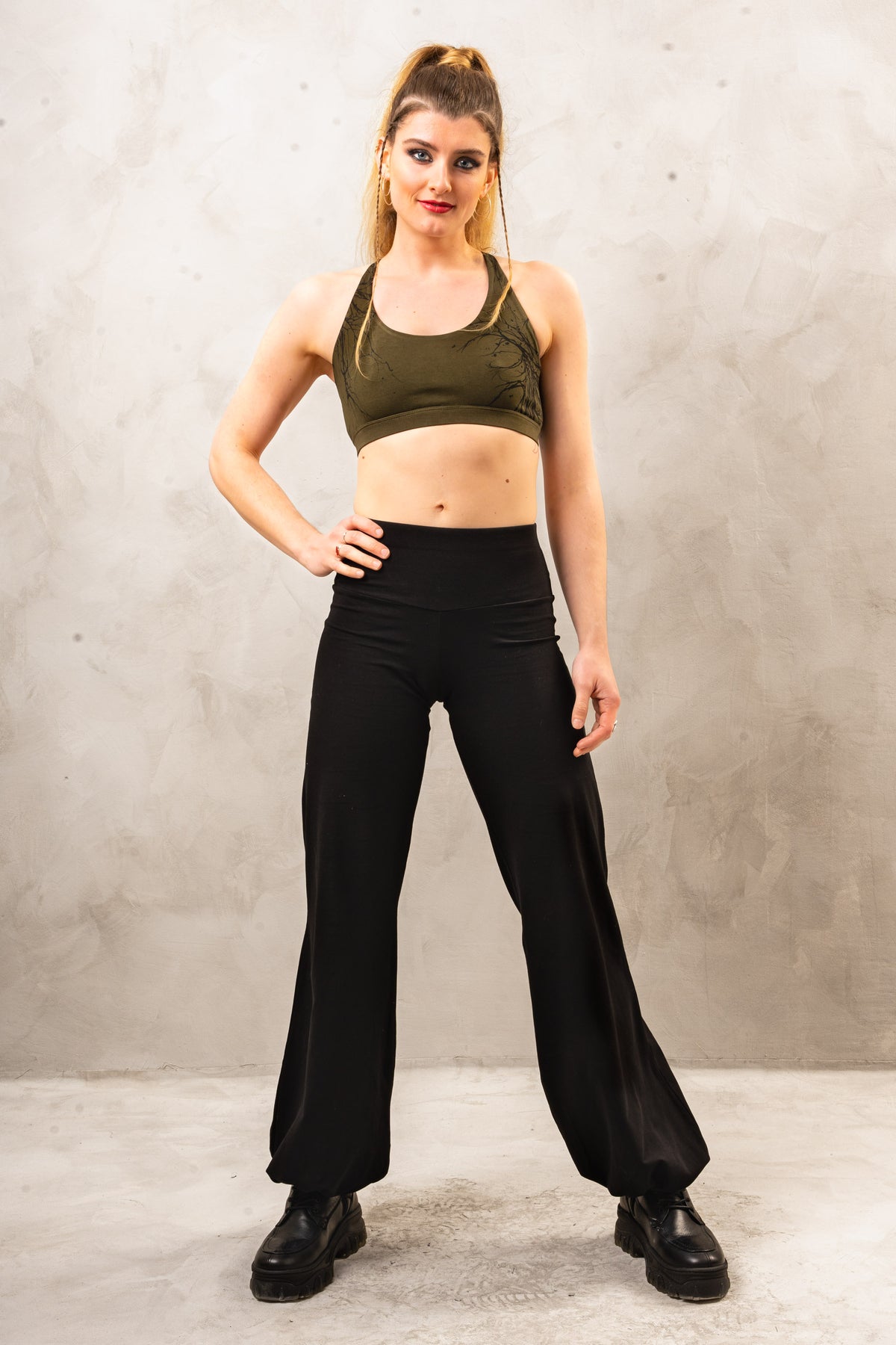a woman posing for a picture in a crop top and wide legged pants