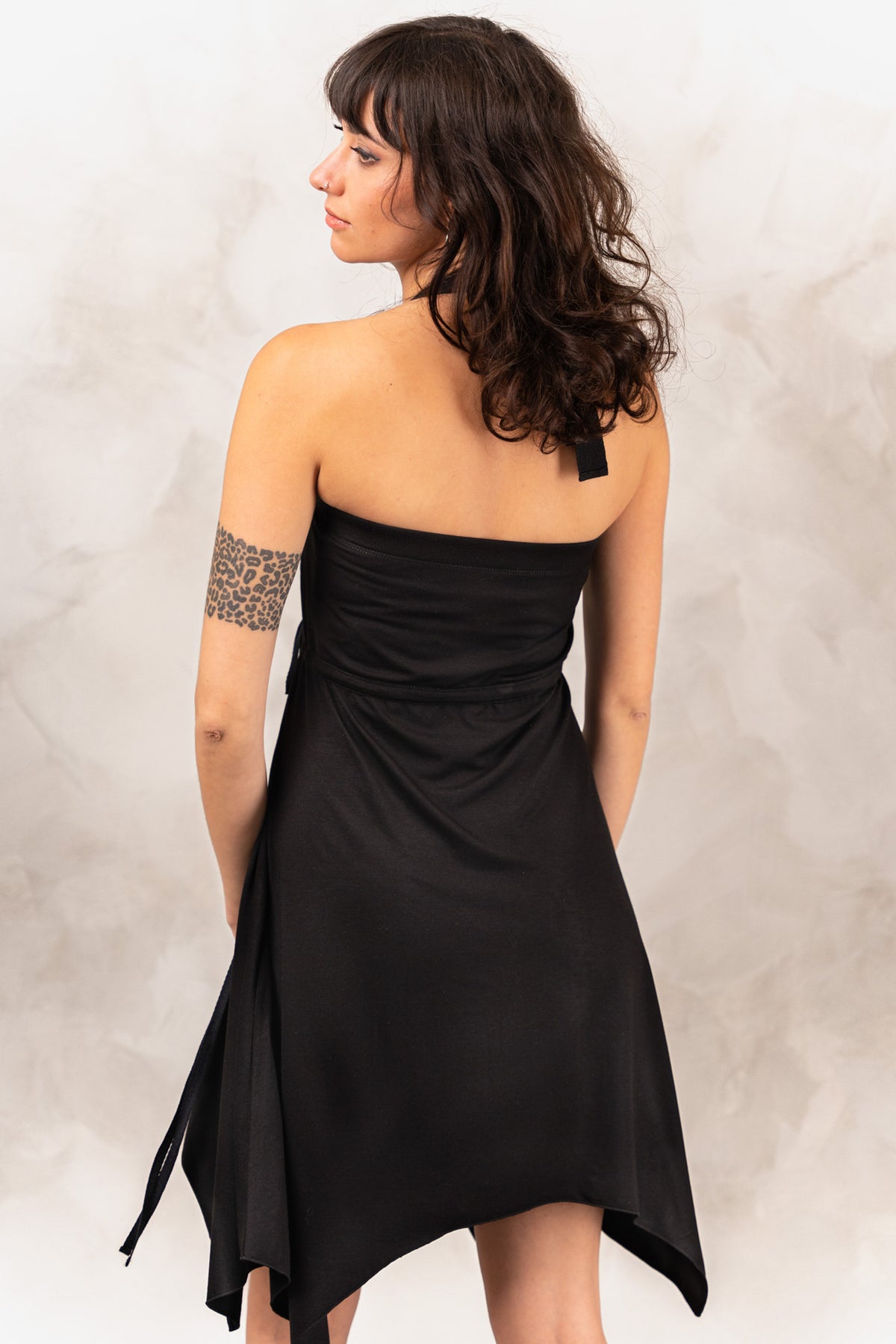 a woman in a black dress with a tattoo on her arm
